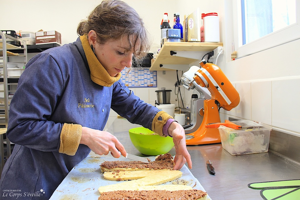 Mélaine Camou-Juncas pose un croustillant sur une génoise pour un letter cake. Pâtisserie Neü en Béarn.